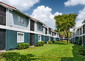 Thumbnail 25 of 28 - A row of houses with green lawns and trees in front.
