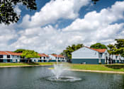 Thumbnail 24 of 28 - A fountain in the middle of a lake in front of a building.