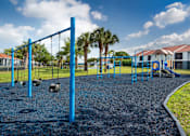 Thumbnail 15 of 28 - A playground with a blue swing set and a gravel ground.