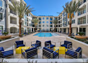 Thumbnail 2 of 21 - A pool surrounded by blue chairs and palm trees.