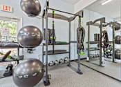 Thumbnail 22 of 34 - A gym with a variety of equipment including a squat rack, a bench, and a mirror.