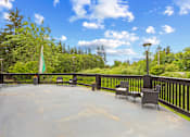 Thumbnail 26 of 34 - A patio with chairs and a table is surrounded by trees.