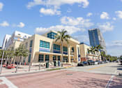 Thumbnail 6 of 9 - Downtown Miami, FL Apartments – The Anamar at Collins Park – A library with a glass facade and palm trees in front.