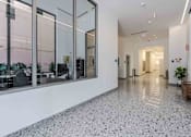 Thumbnail 24 of 37 - A long hallway with a tiled floor and glass walls on one side.