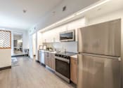 Thumbnail 1 of 37 - Modern kitchen in a pet-friendly Miami Beach apartment featuring energy-efficient appliances, sleek countertops, a built-in microwave, refrigerator, and dishwasher in an open-concept layout.