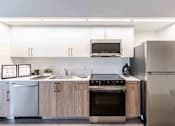 Thumbnail 4 of 37 - Modern pet-friendly apartment home in Miami Beach, Florida, showcasing an open-concept layout with energy-efficient appliances, sleek built-in microwave, refrigerator, and dishwasher in a stylish kitchen.
