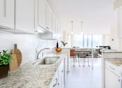 Thumbnail 18 of 66 - A kitchen with white cabinets and a marble countertop.