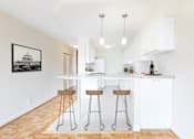 Thumbnail 23 of 66 - A kitchen with white cabinets and a framed picture of a building on the wall.