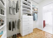 Thumbnail 17 of 66 - A white closet with clothes hanging and shoes on the floor.