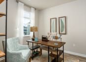 Thumbnail 25 of 62 - a home office with two paintings on the wall and a wooden desk with a chair and a