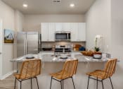 Thumbnail 14 of 62 - a kitchen with a counter top and three chairs