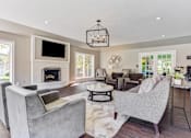 Thumbnail 15 of 15 - Apartments in Geneva, IL for Rent- Ashford at Geneva-  A modern living room with a grey sofa and a fireplace.