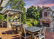 Thumbnail 11 of 15 - Apartments in Geneva, IL for Rent- Ashford at Geneva-  A patio with a table and chairs and a fireplace.
