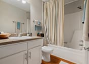 Thumbnail 29 of 29 - A bathroom with a white toilet, sink, and striped shower curtain.