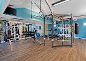 Thumbnail 21 of 29 - A gym with a variety of equipment including weights and a pull up bar.