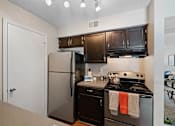 Thumbnail 26 of 29 - A kitchen with black appliances and wooden cabinets.