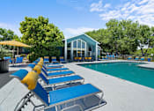 Thumbnail 6 of 29 - A poolside area with sun loungers and a building in the background.