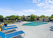 Thumbnail 7 of 29 - A pool area with sun loungers and a small building.