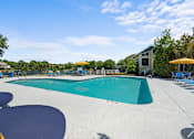 Thumbnail 8 of 29 - A large outdoor swimming pool with a blue tiled edge and a yellow umbrella.