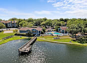 Thumbnail 1 of 29 - A dock extends into a body of water in front of a residential area.