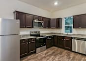 Thumbnail 72 of 75 - A kitchen with brown cabinets and stainless steel appliances.