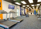 Thumbnail 3 of 46 - Newly Renovated Apartments in Mesa, AZ - Mesa Station Apartments - Fitness Center With Treadmills, Exercise Bikes, Strength Equipment, Wall-Mounted Televisions, And Bright Overhead Lighting.