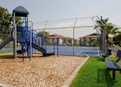 Thumbnail 34 of 46 - Mesa, AZ, Apartments for Rent - Mesa Station - Playground with Slides, Wood-Chips, Benches, Surrounded by Grass.