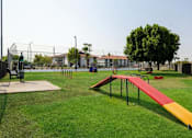 Thumbnail 35 of 46 - a park with a seesaw and benches on the grass