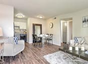 Thumbnail 9 of 46 - Apartments in Mesa, AZ, for Rent - Mesa Station - Open Concept Living Room with Wood-Style Flooring, Decorative Rug, Coffee Table, Couch, Chair with Decorative Pillows, and Access to the Dining Area and Kitchen.