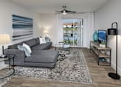 Thumbnail 7 of 28 - A living room with a grey couch, a rug, a table, and a ceiling fan.