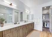 Thumbnail 19 of 41 - Skye Canyon, NV Townhomes Near The Las Vegas Strip - Banyan Brighton - Bathroom with Wood-Inspired Flooring and Cabinets, White Counters, and an Oversized Closet with Carpet