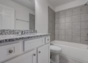Thumbnail 25 of 36 - A white bathroom with a tub, toilet, and sink.