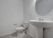 Thumbnail 24 of 36 - A white toilet and sink in a bathroom.