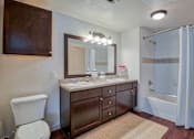 Thumbnail 20 of 33 - bathroom with cabinets above toilet and below single sink with a big mirror and bathtub and lights on ceiling