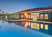Thumbnail 11 of 28 - A building with a pool in front of it is lit up at dusk.