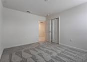 Thumbnail 31 of 36 - A room with a carpeted floor and a doorway leading to another room.