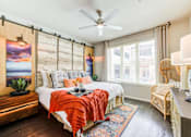 Thumbnail 3 of 17 - A bedroom with a bed, chair, and a painting on the wall.