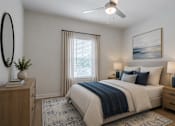 Thumbnail 6 of 18 - Spacious primary bedroom at Blue Sky Landing in College Park, GA featuring a ceiling fan, large windows, plush carpeting, and modern finishes in a brand-new one-, two-, and three-bedroom apartment home.