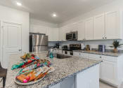 Thumbnail 4 of 30 - Boatman Hammock Townhomes in Lake Worth, FL photo of a kitchen with white cabinets and granite counter tops and a sink