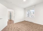 Thumbnail 13 of 26 - A room with a carpeted floor and a window with blinds.