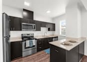 Thumbnail 1 of 26 - A kitchen with black cabinets and stainless steel appliances.