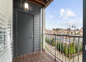 Thumbnail 17 of 26 - A black door is on the left side of a balcony with a wooden floor.
