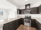 Thumbnail 2 of 26 - A modern kitchen with a stove and microwave built into the cabinetry.