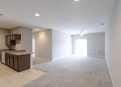 Thumbnail 13 of 21 - an empty living room and kitchen with an open door to the bedroom