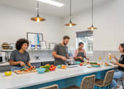 Thumbnail 12 of 35 - Four people are cooking and eating in a modern kitchen.