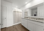 Thumbnail 24 of 35 - A white bathroom with a wooden floor and a mirror above the sink.
