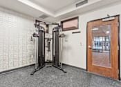 Thumbnail 29 of 42 - A gym room with a squat rack and a mirror.