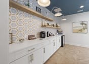 Thumbnail 23 of 35 - Pet-Friendly Apartments in Savannah, GA – The Palms at Chatham – a kitchen with white cabinets and blue tiles on the wall from our clubhouse