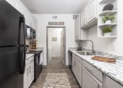 Thumbnail 1 of 35 - Savannah, GA Apartments – The Palms at Chatham– a kitchen with white cabinets and black appliances