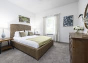 Thumbnail 10 of 35 - Savannah, GA Apartments – The Palms at Chatham– a bedroom with a large bed and a dresser with a lamp